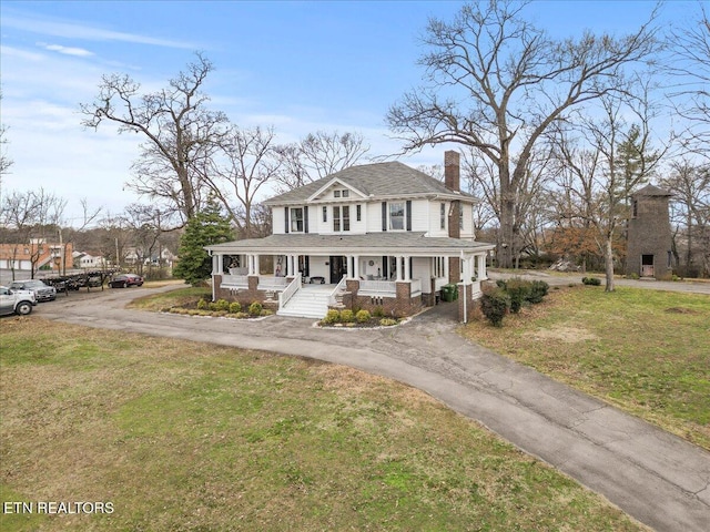 view of front of home with covered porch and a front lawn