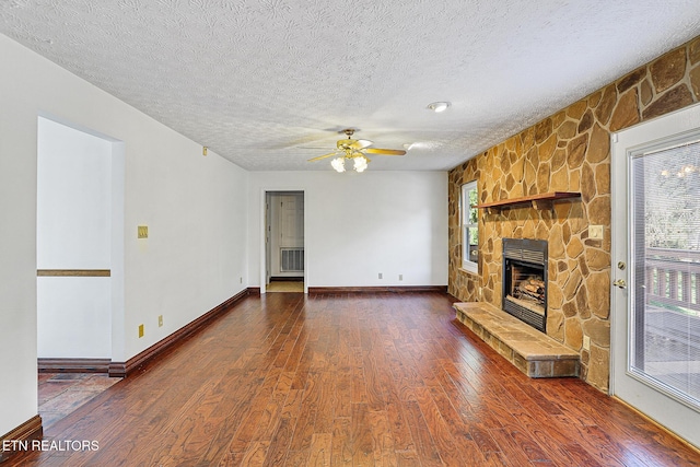 unfurnished living room featuring ceiling fan, a textured ceiling, a fireplace, and dark hardwood / wood-style flooring
