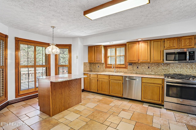 kitchen with appliances with stainless steel finishes, decorative light fixtures, sink, backsplash, and a center island