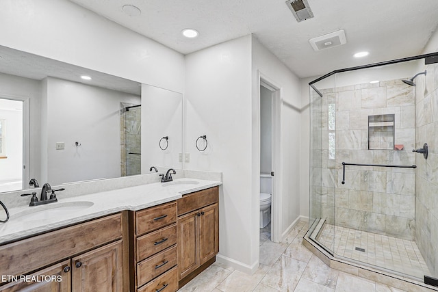 bathroom featuring vanity, a textured ceiling, a shower with door, and toilet
