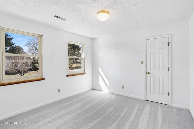 carpeted empty room featuring a textured ceiling