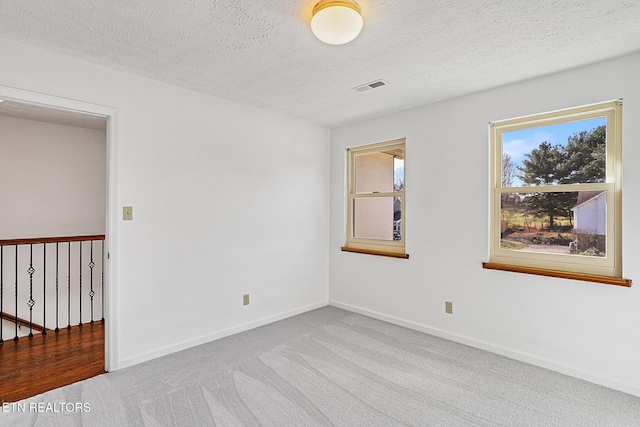 carpeted empty room featuring a textured ceiling