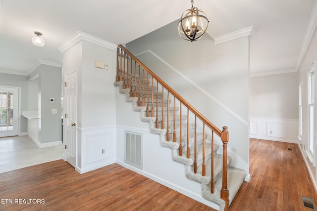 stairway with visible vents, a chandelier, and hardwood / wood-style flooring