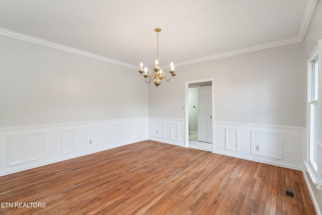 spare room with light wood-type flooring, visible vents, a notable chandelier, and crown molding