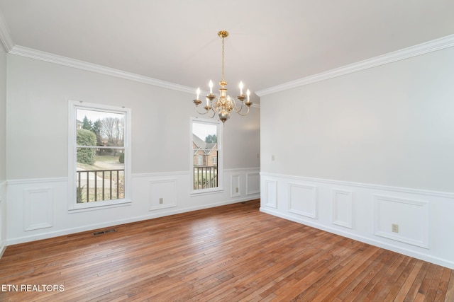 empty room featuring visible vents, a chandelier, ornamental molding, and light wood-style flooring