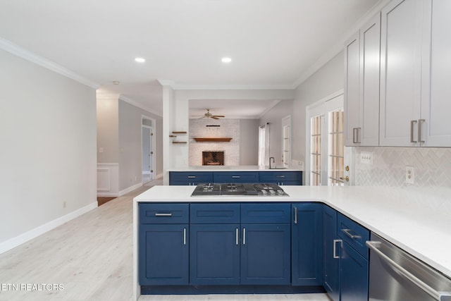 kitchen featuring appliances with stainless steel finishes, a peninsula, light countertops, and ornamental molding