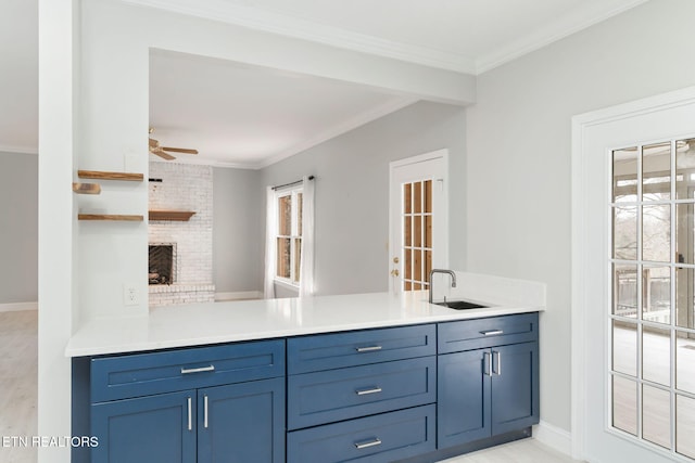 kitchen with ceiling fan, light countertops, ornamental molding, a peninsula, and a sink