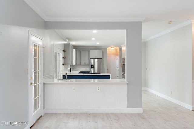 kitchen with a sink, light wood-type flooring, stainless steel refrigerator with ice dispenser, and ornamental molding