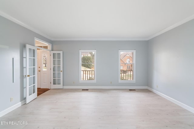 spare room with baseboards, crown molding, and light wood finished floors