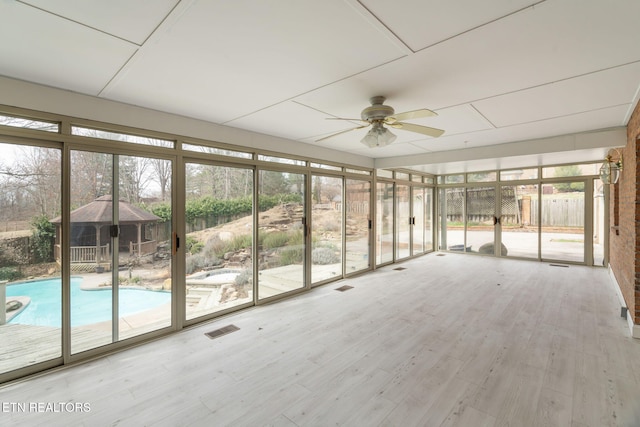 unfurnished sunroom featuring visible vents and ceiling fan