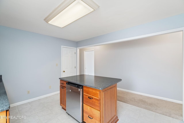 kitchen featuring brown cabinetry, baseboards, a kitchen island, refrigerator, and light carpet