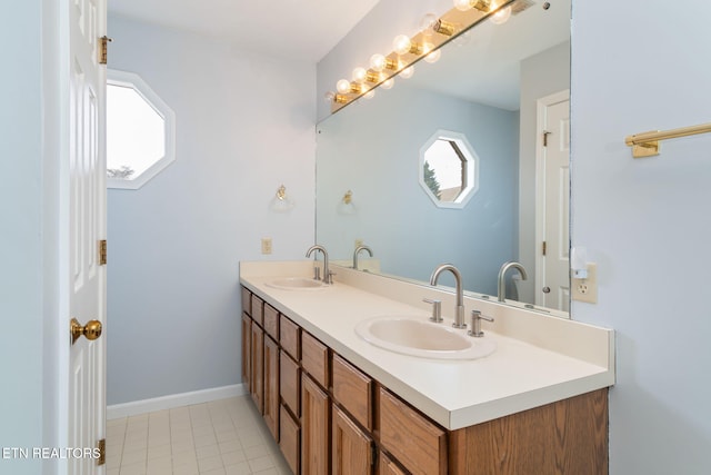 bathroom featuring a sink, baseboards, double vanity, and tile patterned flooring