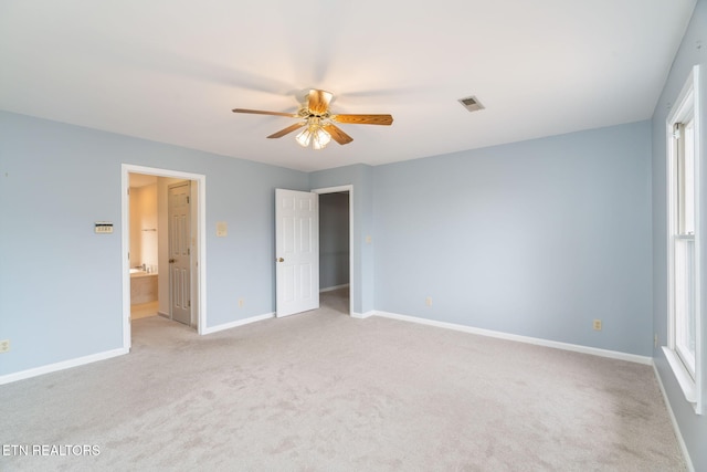 unfurnished bedroom featuring a ceiling fan, baseboards, visible vents, light colored carpet, and connected bathroom