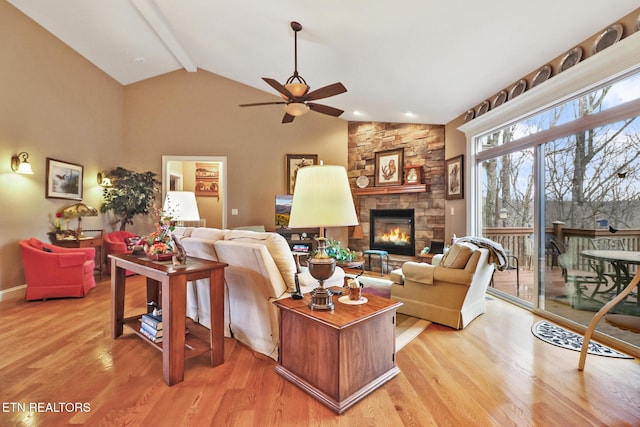 living room with a stone fireplace, high vaulted ceiling, ceiling fan, beam ceiling, and light hardwood / wood-style flooring