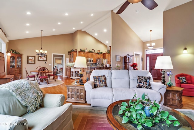 living room featuring ceiling fan with notable chandelier, wood-type flooring, and high vaulted ceiling