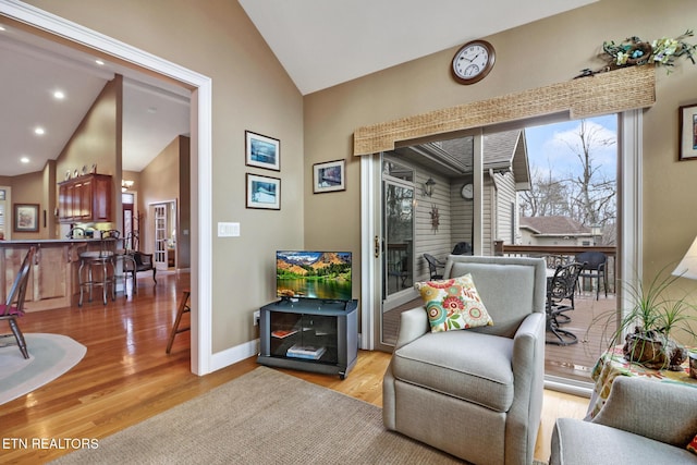 sitting room with lofted ceiling, indoor bar, and light wood-type flooring