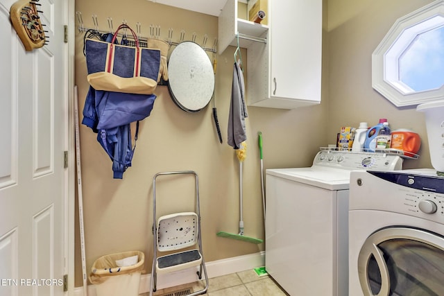 laundry room with washer and clothes dryer, cabinets, and light tile patterned flooring