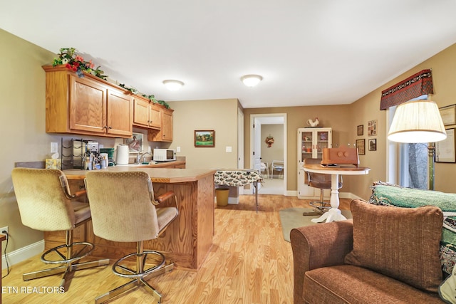 kitchen featuring kitchen peninsula, light hardwood / wood-style floors, and a breakfast bar area