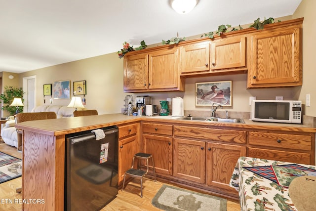 kitchen featuring sink, dishwashing machine, light hardwood / wood-style floors, and kitchen peninsula