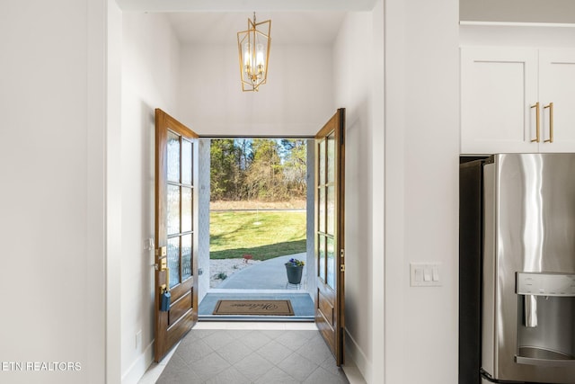 doorway with tile patterned floors, baseboards, and an inviting chandelier