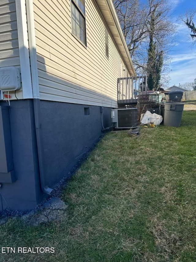 view of side of property with a yard and central AC