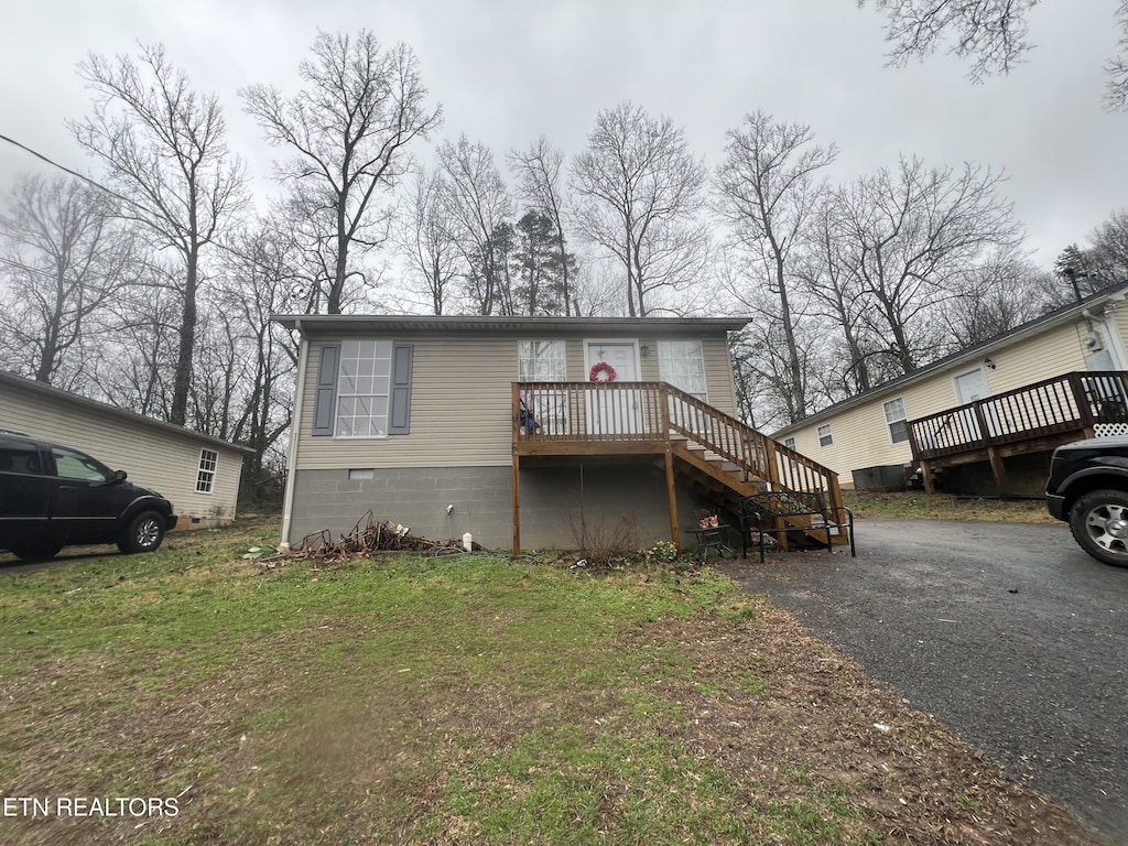 view of front of property with a wooden deck and a front yard