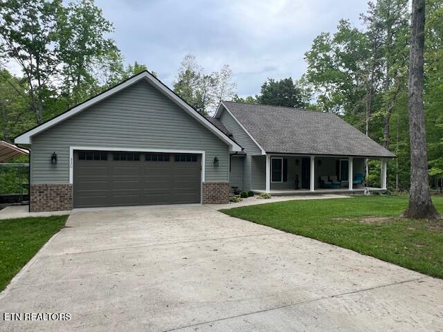 330 Cumberland Cove Rd, Monterey, TN 38574 - view of front of home with brick siding, a porch, concrete driveway, a garage, and a front lawn