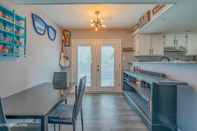 kitchen with french doors, white cabinetry, dark hardwood / wood-style flooring, a notable chandelier, and light stone countertops