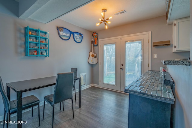 dining area with dark hardwood / wood-style floors, a notable chandelier, and french doors