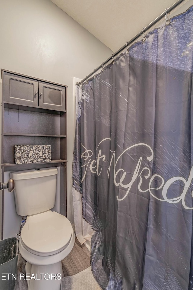 bathroom featuring walk in shower and toilet