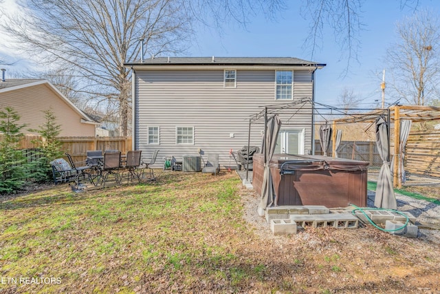 rear view of house featuring a hot tub and a lawn