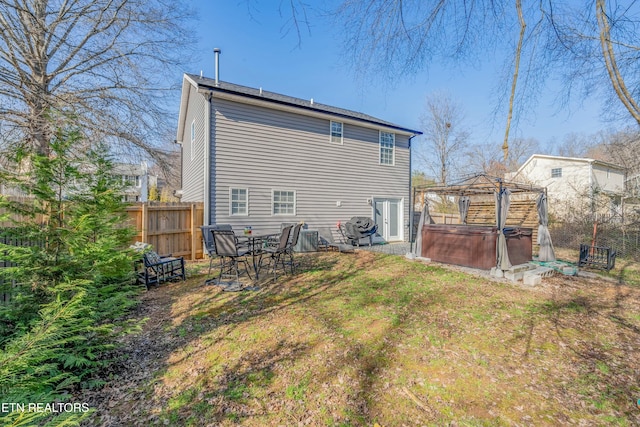 back of property featuring a gazebo, a hot tub, and a lawn