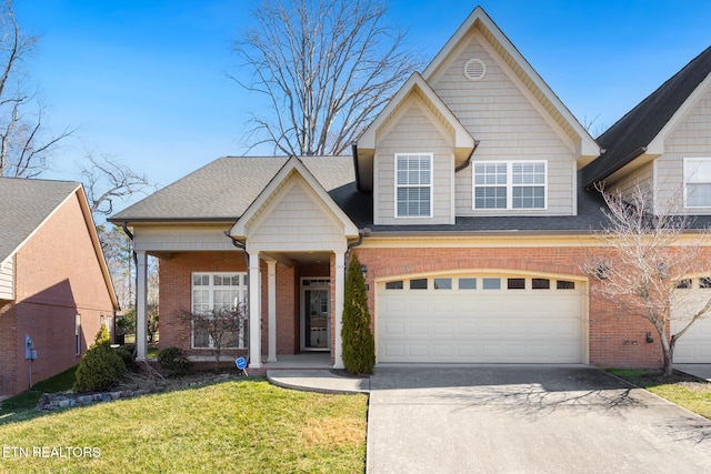 traditional-style house with a shingled roof, concrete driveway, brick siding, and a front lawn