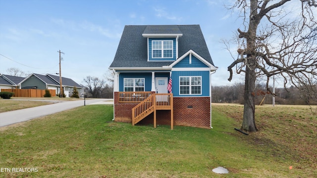 view of front of house featuring driveway, a shingled roof, a front lawn, and brick siding