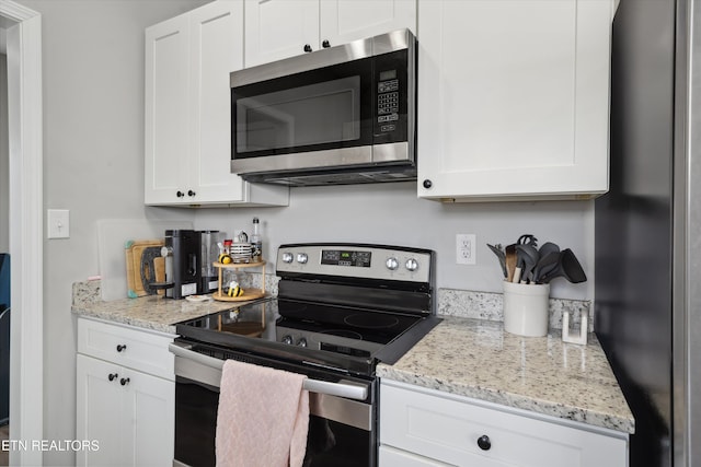 kitchen featuring appliances with stainless steel finishes, white cabinetry, and light stone counters