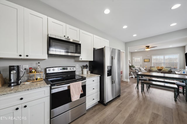 kitchen featuring open floor plan, appliances with stainless steel finishes, and white cabinetry