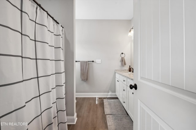 bathroom with baseboards, wood finished floors, and vanity