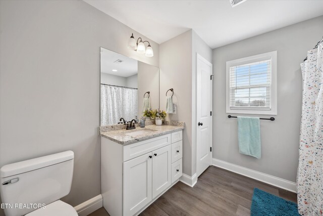 bathroom featuring toilet, baseboards, wood finished floors, and vanity