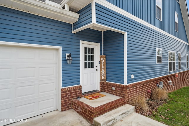 view of exterior entry with a garage and brick siding