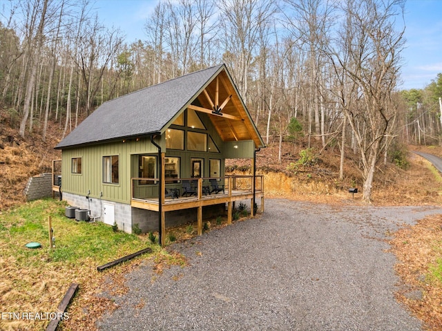 rustic home featuring a shingled roof and gravel driveway