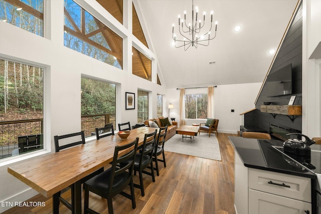 dining space with an inviting chandelier, baseboards, high vaulted ceiling, and wood finished floors