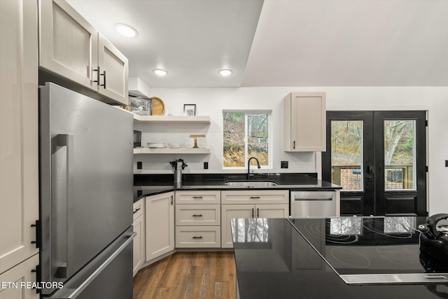 kitchen featuring dark wood-style flooring, a sink, appliances with stainless steel finishes, open shelves, and dark countertops