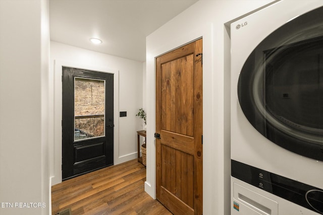 washroom featuring stacked washing maching and dryer, visible vents, laundry area, and dark wood-type flooring