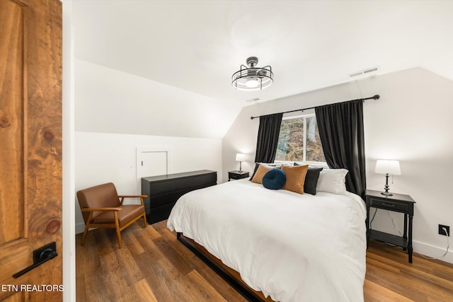 bedroom with lofted ceiling, wood finished floors, visible vents, and baseboards