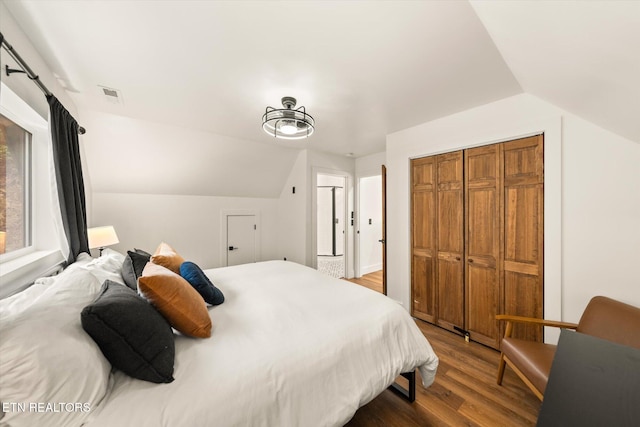 bedroom featuring vaulted ceiling, a closet, wood finished floors, and visible vents