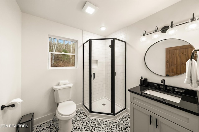 bathroom with a stall shower, baseboards, vanity, and toilet