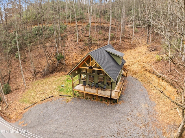 view of front of property with gravel driveway, a wooded view, metal roof, and a ceiling fan