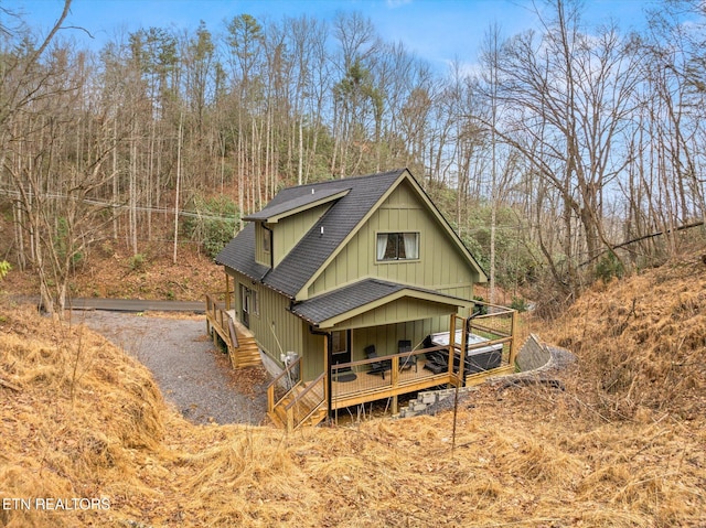 view of front of home with a shingled roof, gravel driveway, and a wooden deck