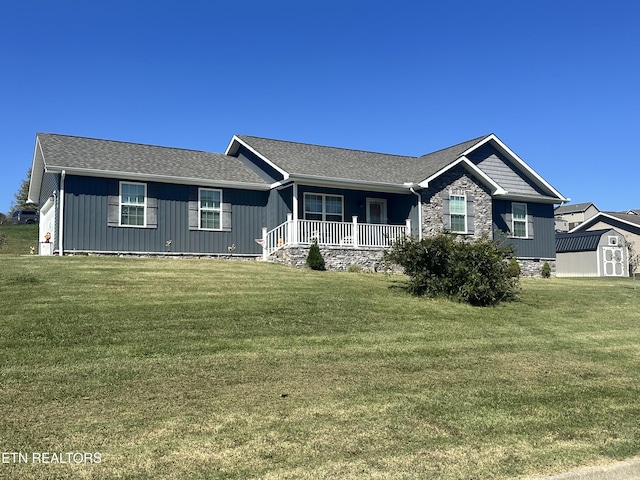 ranch-style house featuring a storage unit, covered porch, and a front yard