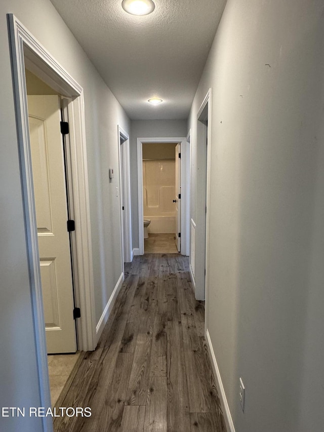 hallway featuring hardwood / wood-style flooring and a textured ceiling